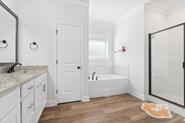 bathroom featuring vanity, hardwood / wood-style flooring, ornamental molding, and shower with separate bathtub