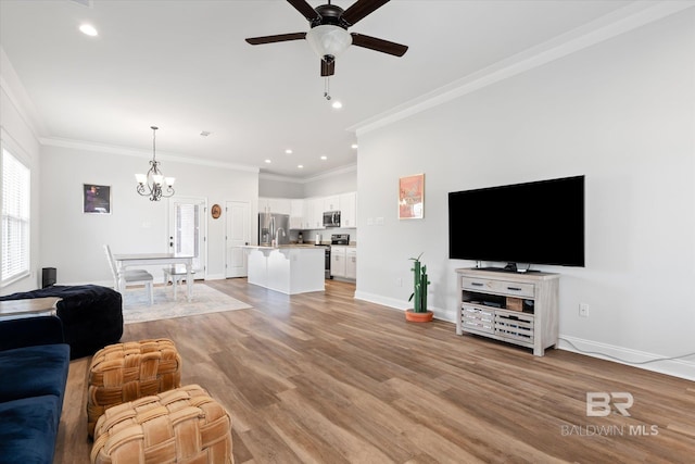 living room featuring ceiling fan with notable chandelier, light hardwood / wood-style flooring, and ornamental molding