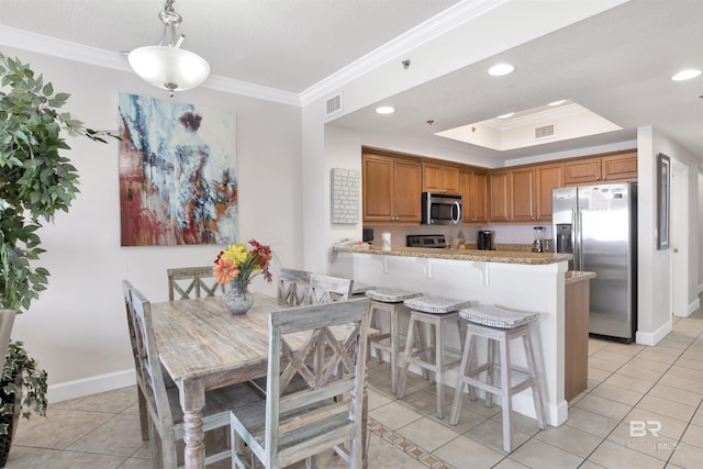 kitchen featuring kitchen peninsula, stainless steel appliances, a tray ceiling, crown molding, and light tile patterned floors