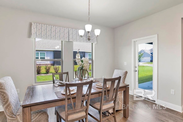 dining space featuring dark wood-type flooring and a notable chandelier