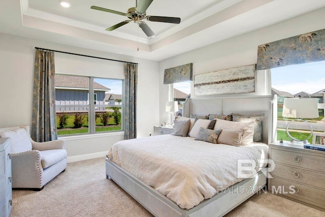 bedroom with ceiling fan, a tray ceiling, and light colored carpet