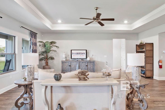 living room with hardwood / wood-style flooring, a raised ceiling, and ornamental molding