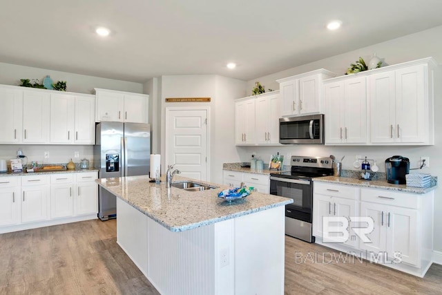 kitchen featuring white cabinets, light hardwood / wood-style flooring, sink, a kitchen island with sink, and appliances with stainless steel finishes