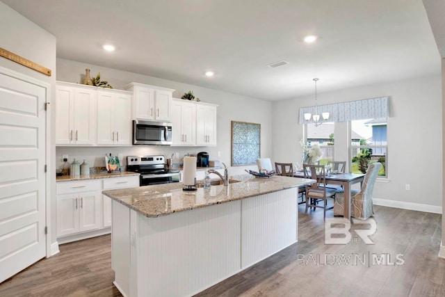 kitchen featuring stainless steel appliances, white cabinetry, a center island with sink, and hardwood / wood-style floors