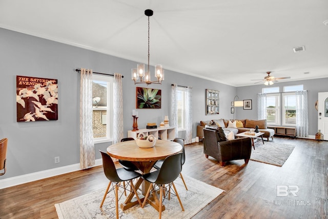 dining space with ceiling fan with notable chandelier, hardwood / wood-style flooring, and ornamental molding