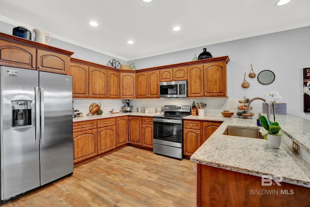 kitchen featuring light hardwood / wood-style floors, sink, kitchen peninsula, stainless steel appliances, and ornamental molding