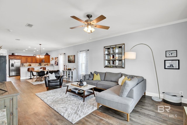 living room featuring ceiling fan, crown molding, and light hardwood / wood-style floors