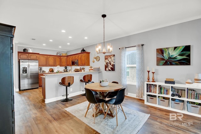 dining room with light hardwood / wood-style flooring, an inviting chandelier, and ornamental molding