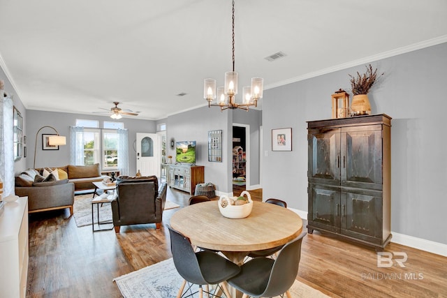 dining room featuring ceiling fan with notable chandelier, light hardwood / wood-style flooring, and crown molding