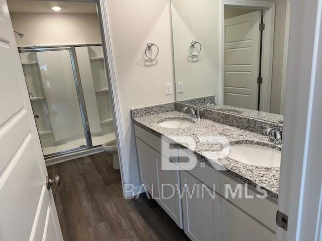 bathroom with toilet, vanity, hardwood / wood-style floors, and a shower with shower door