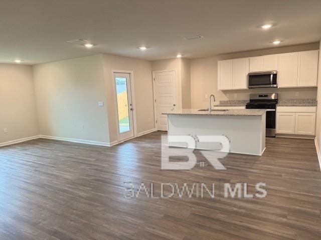 kitchen featuring dark hardwood / wood-style flooring, appliances with stainless steel finishes, an island with sink, and white cabinets