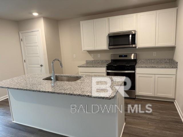 kitchen with white cabinetry, appliances with stainless steel finishes, sink, and a center island with sink