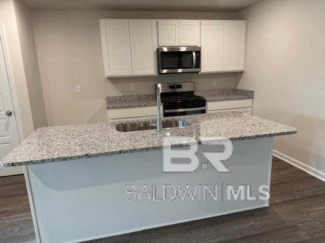 kitchen featuring white cabinets, appliances with stainless steel finishes, a kitchen island with sink, and dark hardwood / wood-style flooring