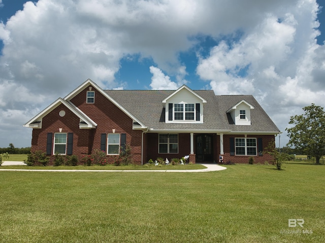 view of front of home featuring brick siding, a front yard, and a shingled roof