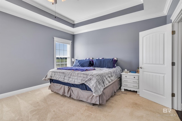 bedroom with a raised ceiling, light carpet, crown molding, and baseboards