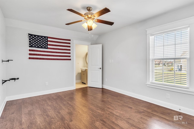 unfurnished bedroom with dark wood-type flooring, connected bathroom, and baseboards