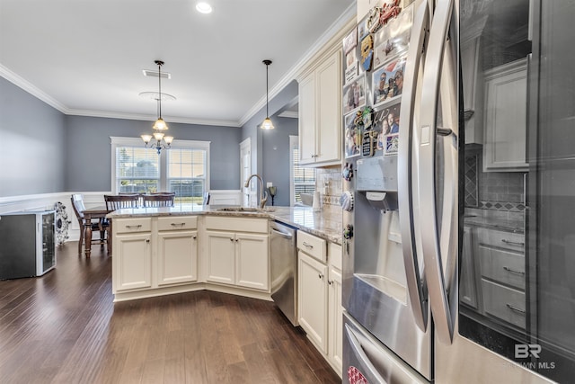 kitchen featuring a peninsula, a sink, appliances with stainless steel finishes, decorative light fixtures, and crown molding