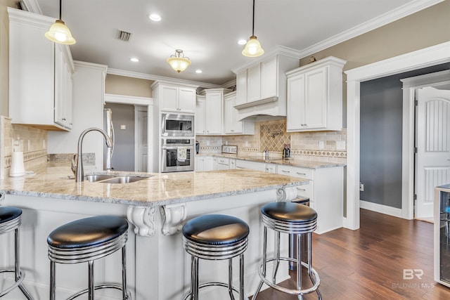 kitchen featuring visible vents, appliances with stainless steel finishes, white cabinetry, pendant lighting, and a sink