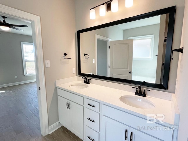 full bath with double vanity, wood tiled floor, baseboards, and a sink