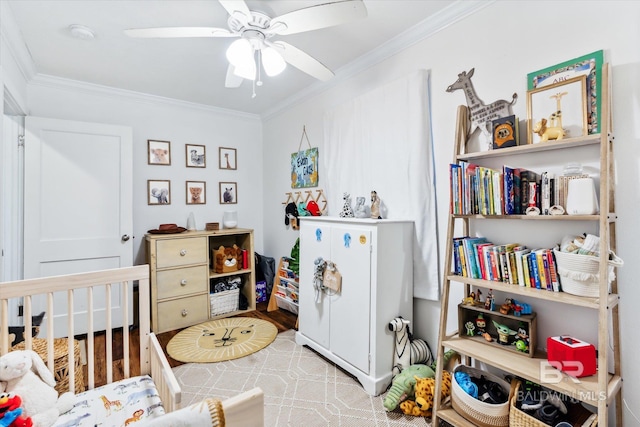 bedroom featuring ceiling fan, crown molding, and a crib