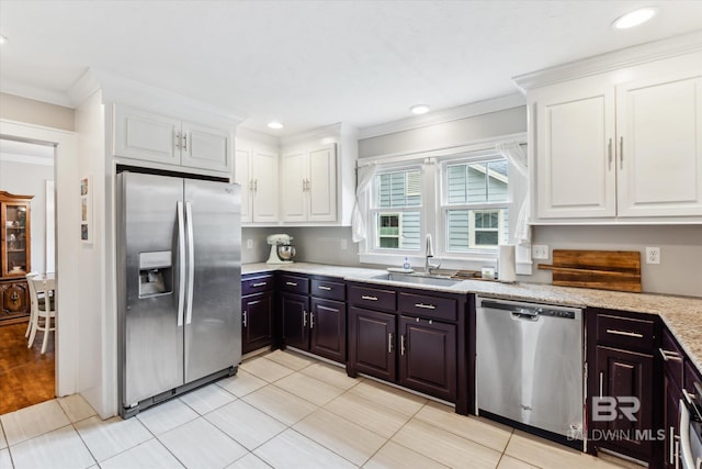 kitchen featuring dark brown cabinetry, white cabinetry, sink, appliances with stainless steel finishes, and ornamental molding