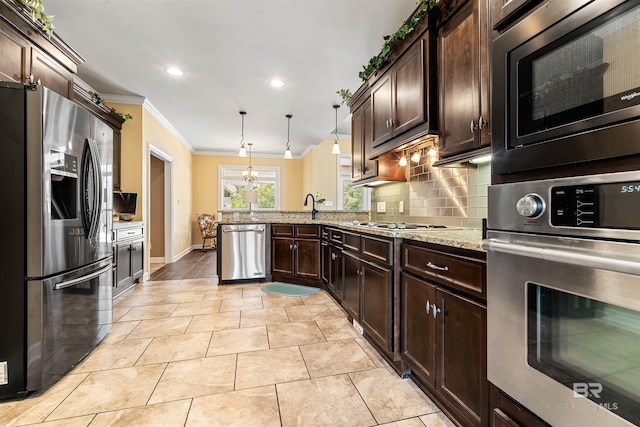 kitchen with decorative light fixtures, crown molding, backsplash, kitchen peninsula, and stainless steel appliances