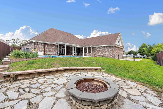 rear view of house featuring a fenced in pool, a patio, an outdoor fire pit, and a lawn