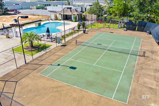 view of tennis court with a playground and a community pool