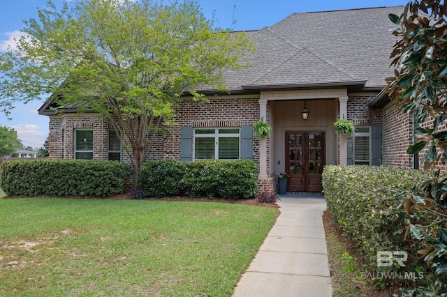 view of front of home featuring brick siding, a front yard, and french doors