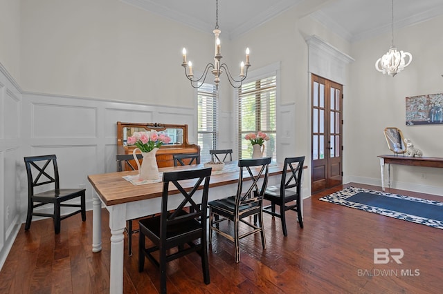 dining space featuring a decorative wall, dark wood-style floors, ornamental molding, and an inviting chandelier