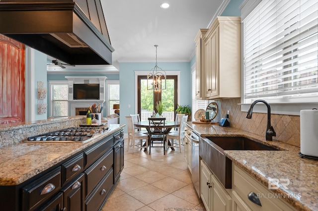 kitchen featuring stainless steel appliances, a sink, decorative backsplash, cream cabinetry, and ornamental molding