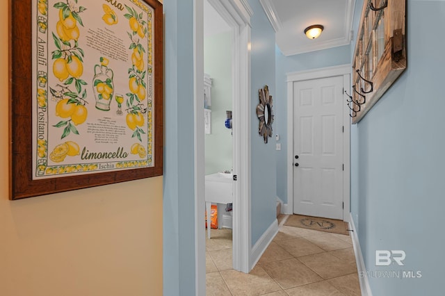 hallway featuring baseboards, crown molding, and light tile patterned floors