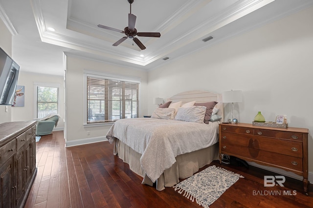 bedroom with a tray ceiling, baseboards, visible vents, crown molding, and dark wood-type flooring