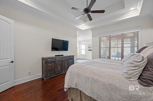 bedroom featuring a tray ceiling, dark wood-style flooring, baseboards, ceiling fan with notable chandelier, and crown molding