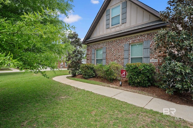 view of side of property with board and batten siding, a lawn, and brick siding