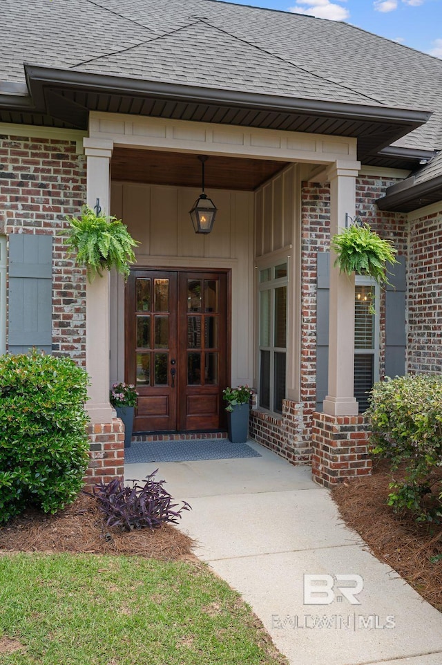 property entrance with brick siding, roof with shingles, and french doors