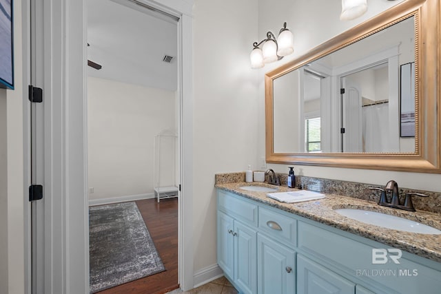 bathroom with baseboards, visible vents, a sink, and double vanity