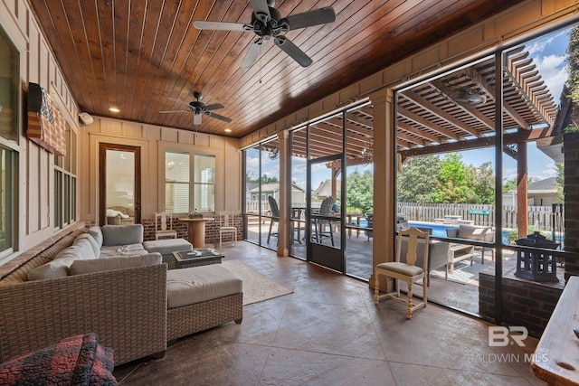 sunroom featuring concrete flooring, a ceiling fan, wooden ceiling, and an outdoor hangout area