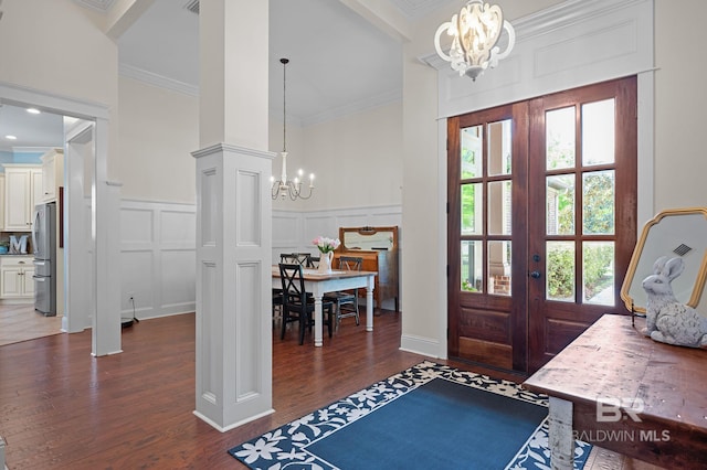 foyer entrance with crown molding, dark wood finished floors, a chandelier, and a decorative wall