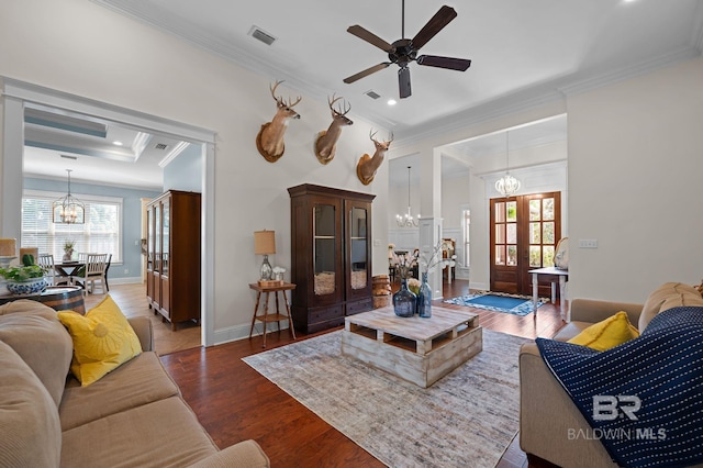 living area with ceiling fan with notable chandelier, wood finished floors, a wealth of natural light, and ornamental molding