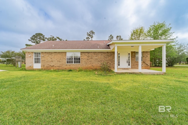 rear view of house featuring a yard, a patio area, and brick siding