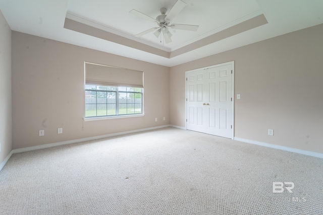 unfurnished bedroom with crown molding, a raised ceiling, baseboards, and light carpet