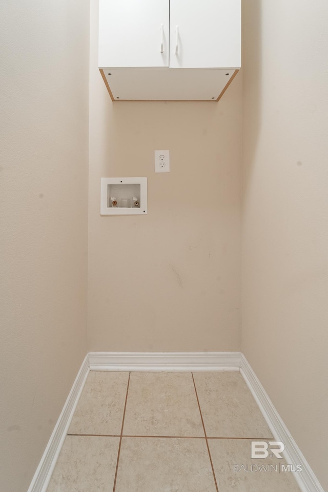 clothes washing area featuring baseboards, hookup for a washing machine, cabinet space, and tile patterned floors