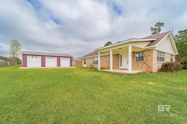 view of front of house featuring a front lawn, brick siding, a detached garage, a patio area, and an outdoor structure