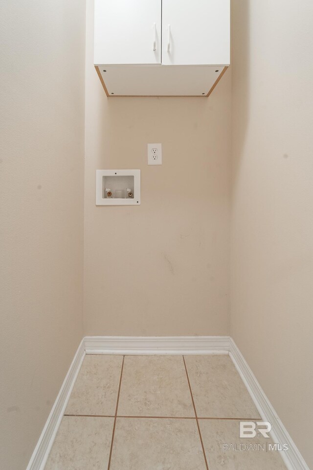 clothes washing area featuring baseboards, hookup for a washing machine, cabinet space, and tile patterned floors