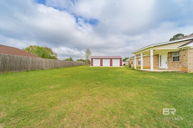 view of yard featuring fence, an outdoor structure, a patio, and a garage
