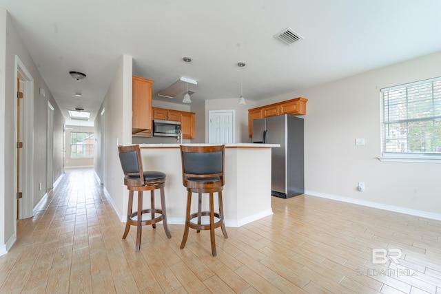 kitchen featuring visible vents, a peninsula, light wood-style flooring, and appliances with stainless steel finishes
