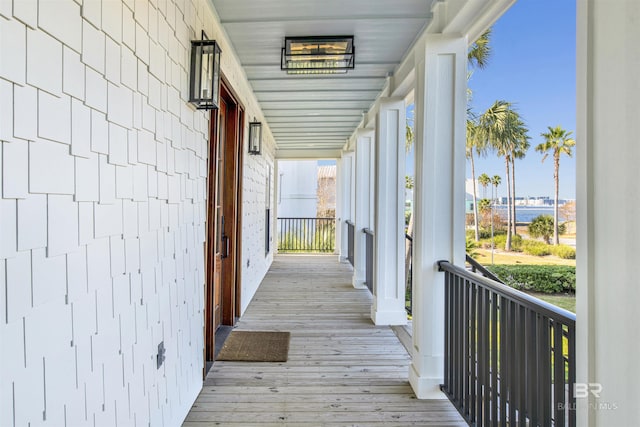 wooden terrace featuring a water view and a porch