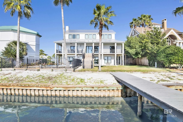 back of property with a yard, a balcony, and a water view