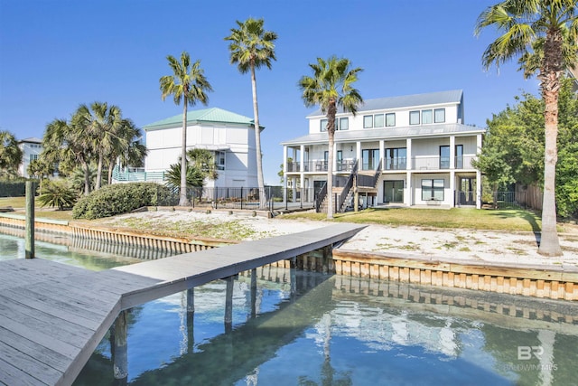 rear view of property featuring a lawn, a balcony, and a water view